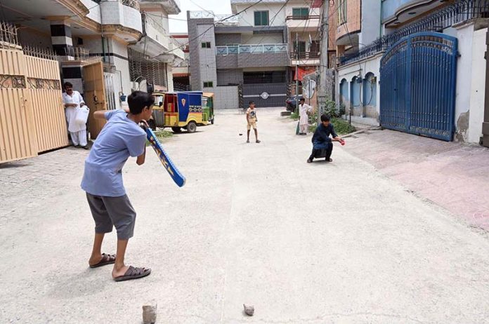 Youngsters enjoy playing cricket in a street