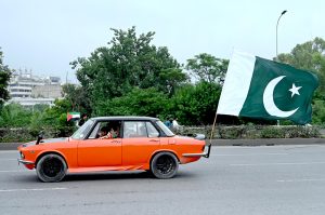 Youngsters having costumes in the colors of national flag of Pakistan skating on the roads to celebrate the 78th Independence Day of Pakistan in the city