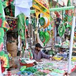 A vendor displaying flags and badges at a roadside stall in connection with Rabi-ul-Awal Celebrations