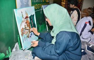 An art student paints her ideas on canvas during a painting competition organized by the Punjab Council of Arts, Faisalabad Division, to mark the Marka-e-Haq and Independence Day celebrations