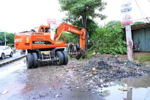 Workers using a heavy machine to clean a blocked sewerage line