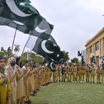 Scouts wave national flags during a ceremony marking Marka-e-Haq (Shuhada Day) as part of Independence Day celebrations at the Governor House