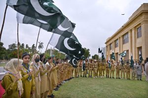 Scouts wave national flags during a ceremony marking Marka-e-Haq (Shuhada Day) as part of Independence Day celebrations at the Governor House