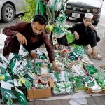 A street vendor arranges festive items to attract patriotic passers-by ahead of Independence Day celebrations at a roadside stall in the federal capital