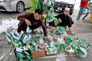 A street vendor arranges festive items to attract patriotic passers-by ahead of Independence Day celebrations at a roadside stall in the federal capital