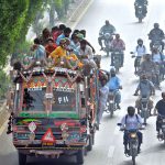 Commuters travel dangerously on the rooftop of a minibus in the Korangi area