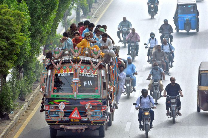 Commuters travel dangerously on the rooftop of a minibus in the Korangi area