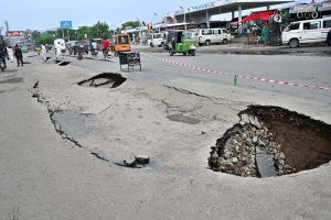 Workers using a heavy machine to clean a blocked sewerage line
