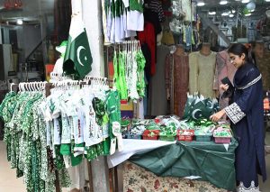 A street vendor arranges festive items to attract patriotic passers-by ahead of Independence Day celebrations at a roadside stall in the federal capital