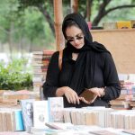A woman browsing books at a book fair at Frere Hall