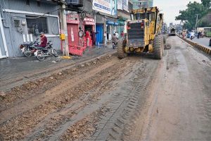 Workers using a heavy machine to clean a blocked sewerage line