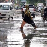 Woman passing through accumulated sewage water at the main road of residential areas of the Gulshan-e-Kaneez Fatima after rain in the city.