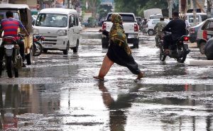 Woman passing through accumulated sewage water at the main road of residential areas of the Gulshan-e-Kaneez Fatima after rain in the city.