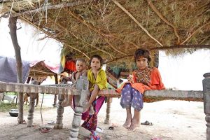 Flood-affected residents of Mehbob Kalhoro village in the Kachha area of the Indus River sit in makeshift huts along the Larkana-Khairpur road after the district administration issued a flood warning