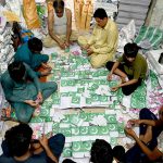Workers tie and pack bundles of printed Pakistani flag buntings to be used in preparations for the upcoming Independence Day celebrations across the country