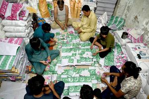 Workers tie and pack bundles of printed Pakistani flag buntings to be used in preparations for the upcoming Independence Day celebrations across the country
