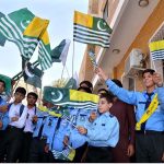 Students hold Pakistani and Kashmiri flags to mark Youm-e-Istehsal at the DC Office.