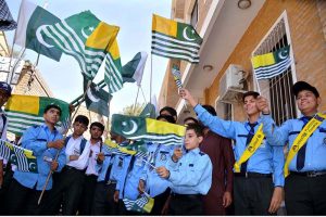 Students hold Pakistani and Kashmiri flags to mark Youm-e-Istehsal at the DC Office.