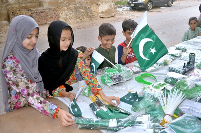 Children selecting national flags and badges from a stall in connection with celebration of 78th Independence Day with the theme of Maarka-E-Haq at Latifabad