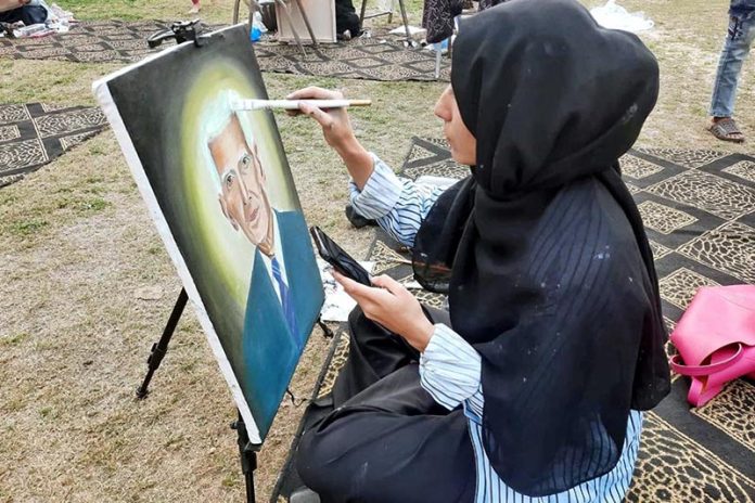 An art student gives final touches to her portrait during an art competition as the nation prepares to celebrate 78th Independence Day