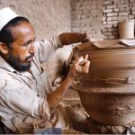 A potter skillfully molding traditional clay pots at his workplace in Musazai