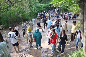 A large number of people enjoy wading through the cool water of a stream in the Margalla Hills trail 5 to escape the intense heat in the Federal Capital