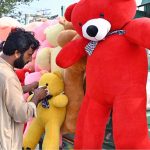 A vendor decorates and displays children’s soft toys to attract customers at his roadside setup