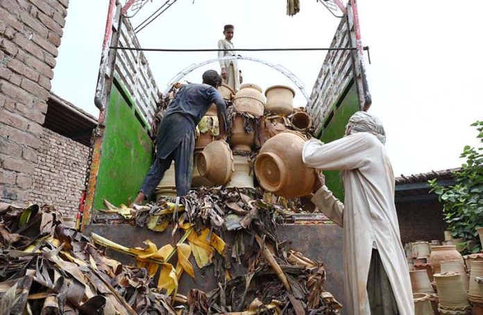 Laborers load plant pots onto a delivery truck for sale in the Musazai area