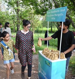 A volunteer distributes seed balls to visitors during the 'Seed Ball Distribution Campaign' organized by Pakistan Tobacco Company (PTC) in collaboration with the Capital Development Authority (CDA) at Trail 5 entrance, encouraging efforts to green the Margalla Hills