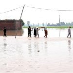 Residents carrying local bed (Charpai) passing through floodwaters to safe place in the Mandi Faizabad District Nankana