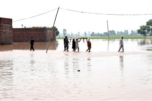 Residents carrying local bed (Charpai) passing through floodwaters to safe place in the Mandi Faizabad District Nankana