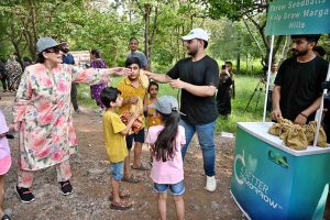 A volunteer distributes seed balls to visitors during the 'Seed Ball Distribution Campaign' organized by Pakistan Tobacco Company (PTC) in collaboration with the Capital Development Authority (CDA) at Trail 5 entrance, encouraging efforts to green the Margalla Hills