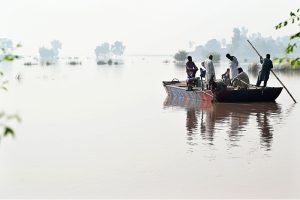 Residents carrying local bed (Charpai) passing through floodwaters to safe place in the Mandi Faizabad District Nankana