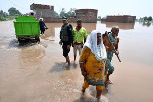 Residents carrying local bed (Charpai) passing through floodwaters to safe place in the Mandi Faizabad District Nankana