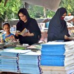 Women select old books from a roadside stall on Mall Road