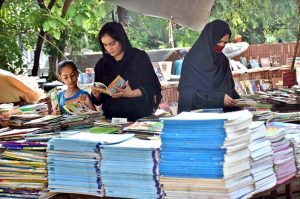 Women select old books from a roadside stall on Mall Road