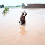 A man wade through the water flooded area of Mandi Faizabad district Nankana