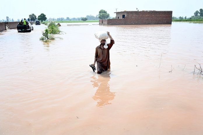 A man wade through the water flooded area of Mandi Faizabad district Nankana