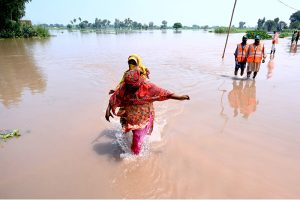 A man wade through the water flooded area of Mandi Faizabad district Nankana