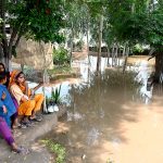 A family sitting outside their house submerged in flood water at Mandi Faizabad district Nankana