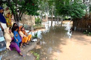 A family sitting outside their house submerged in flood water at Mandi Faizabad district Nankana