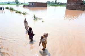 A family sitting outside their house submerged in flood water at Mandi Faizabad district Nankana