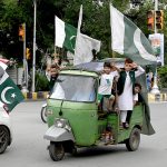 Children celebrating Independence Day of Pakistan riding an auto rickshaw on Mall Road