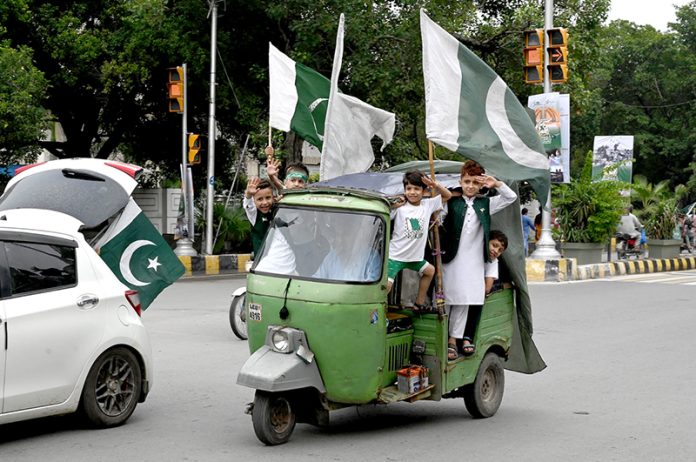 Children celebrating Independence Day of Pakistan riding an auto rickshaw on Mall Road