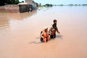 A family sitting outside their house submerged in flood water at Mandi Faizabad district Nankana