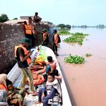 Rescue personnel helps to evacuate a family from the flooded area at Mandi Faizabad district Nankana