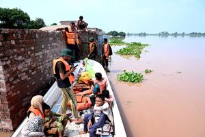 Rescue personnel helps to evacuate a family from the flooded area at Mandi Faizabad district Nankana