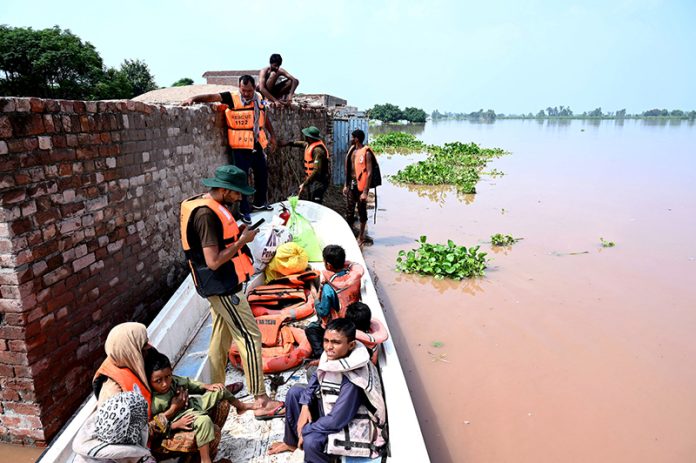 Rescue personnel helps to evacuate a family from the flooded area at Mandi Faizabad district Nankana