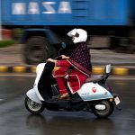 A girl rides her scooty through the rain-soaked streets of the city during a monsoon downpour