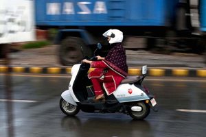A girl rides her scooty through the rain-soaked streets of the city during a monsoon downpour